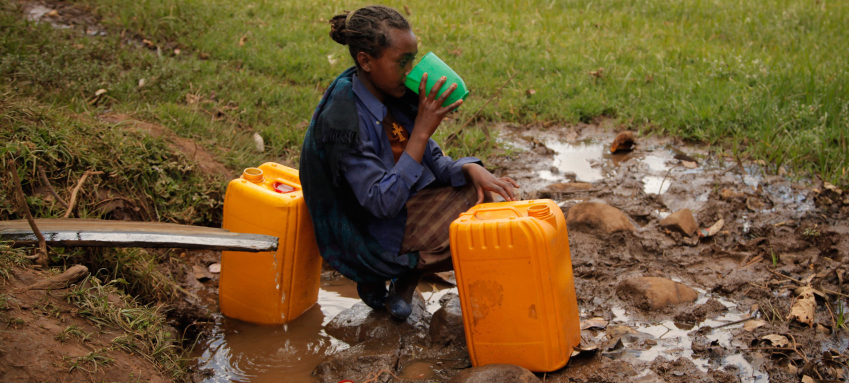 Girl drinks from a contaminated water point in the Jeldu contaminated waterhole