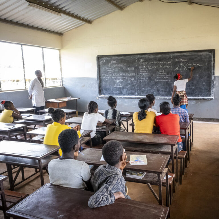 Teachers and pupils write on the blackboard while pupils in a special needs classroom sit at their desks.