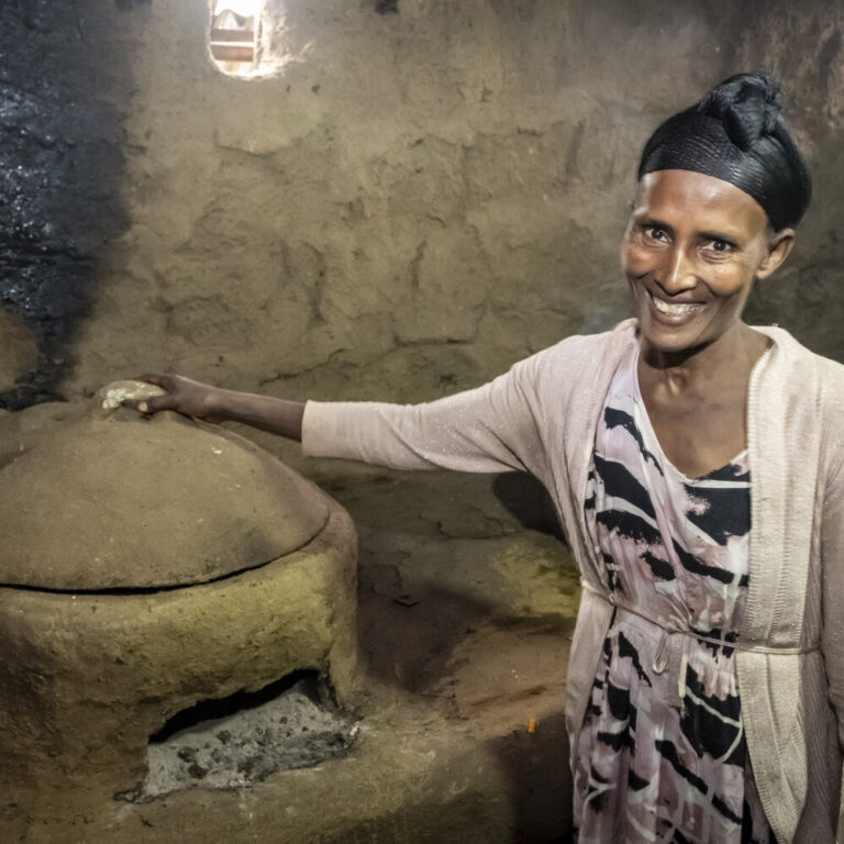 A woman shows her wood-saving stove in her home
