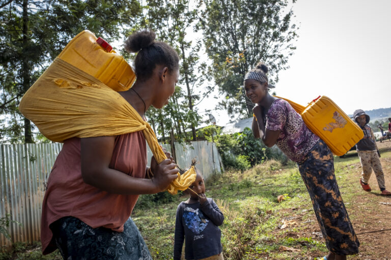 Women carrying water containers on their backs.