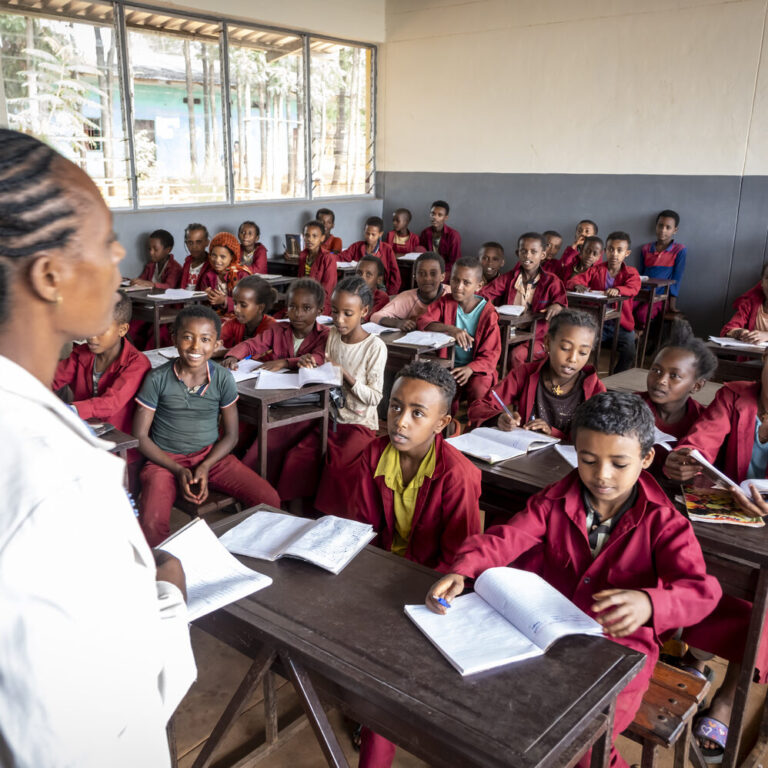 The teacher starts the lesson infront of the children.