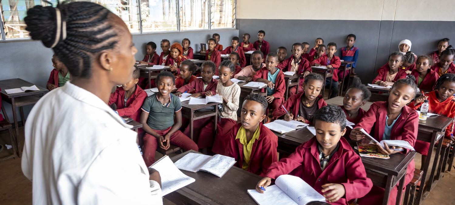 The teacher starts the lesson infront of the children.