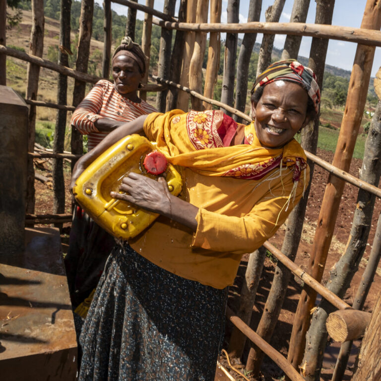 Two women are filling yellow jerry cans with water, helping rural communities gain access to clean water.