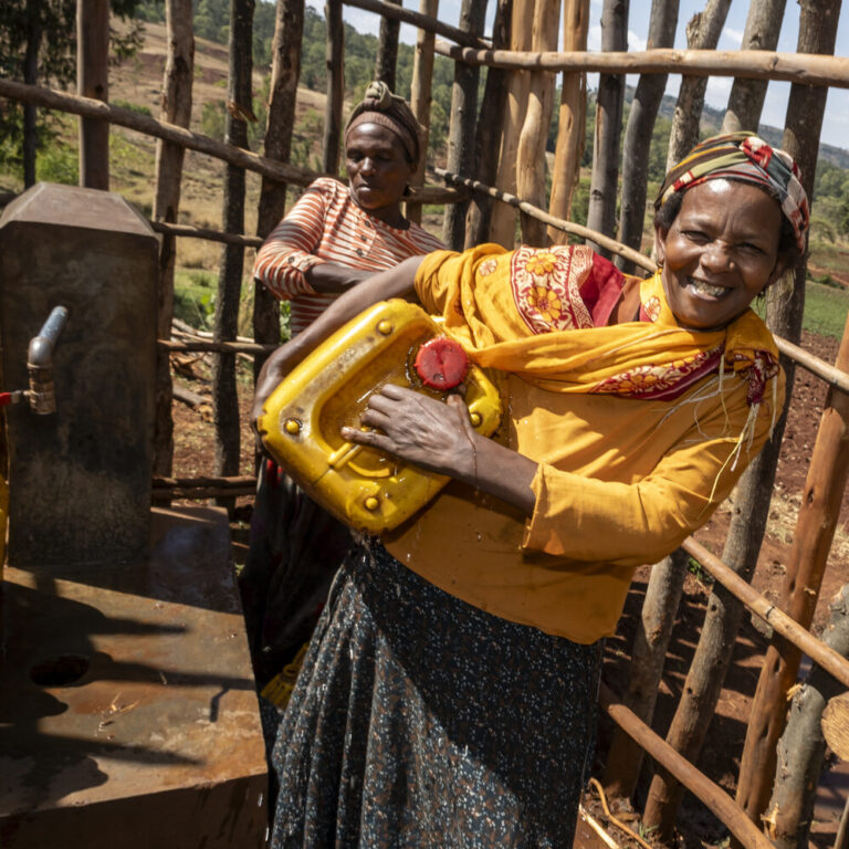 Two women are filling yellow jerry cans with water, helping rural communities gain access to clean water.