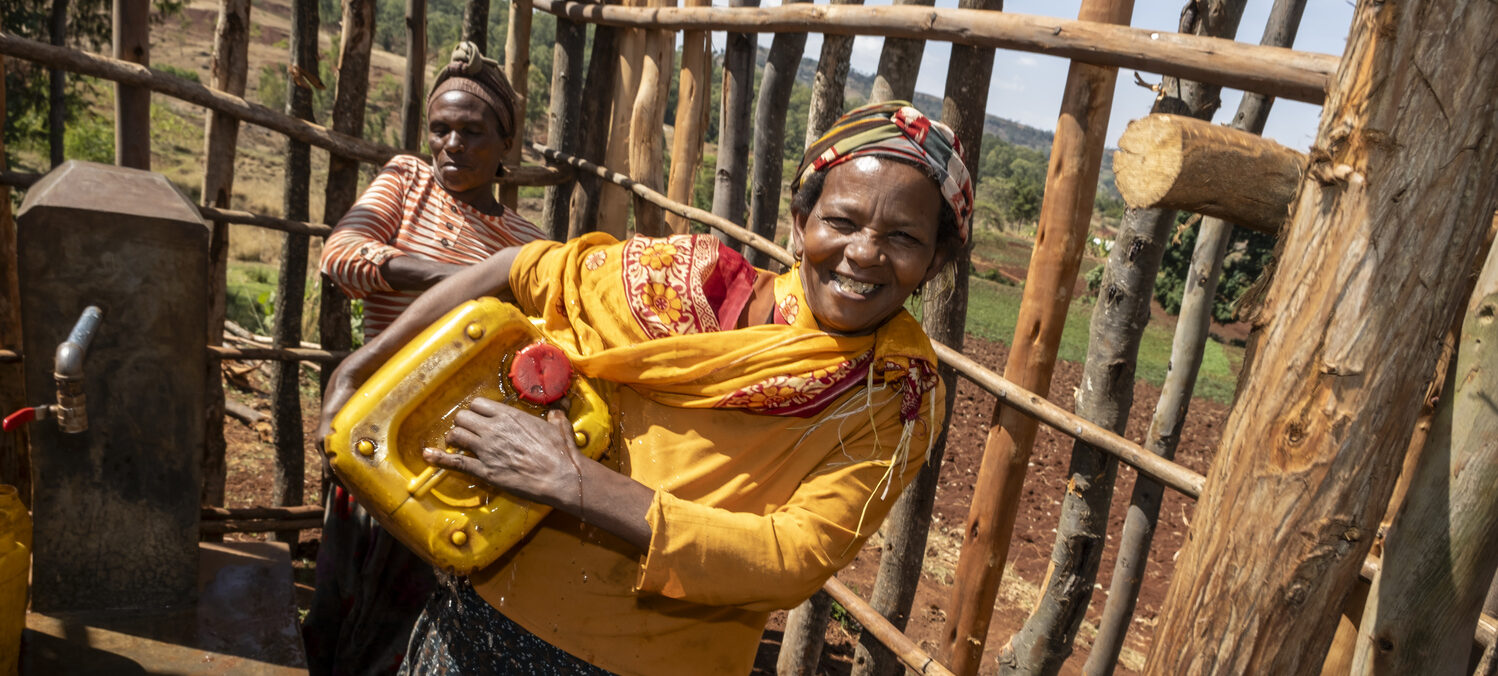 Two women are filling yellow jerry cans with water, helping rural communities gain access to clean water.