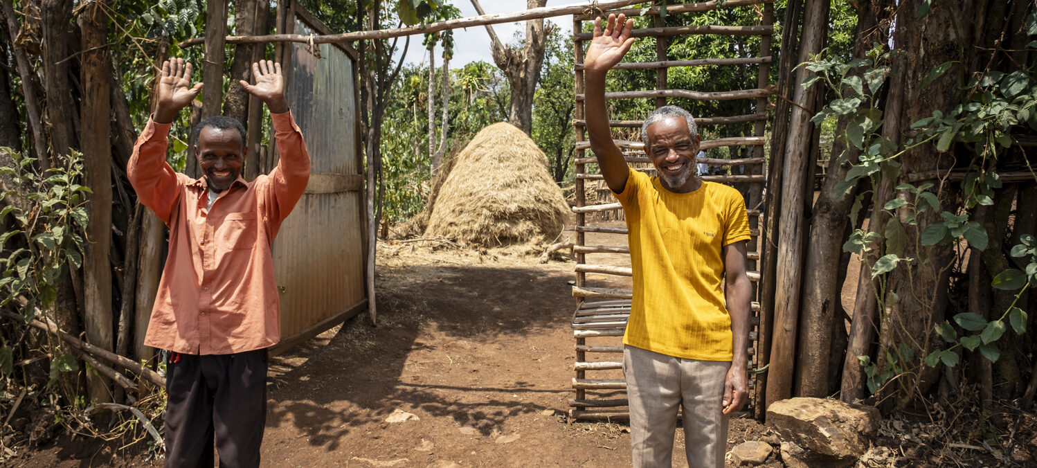 Two men smiling and waving into the camera.