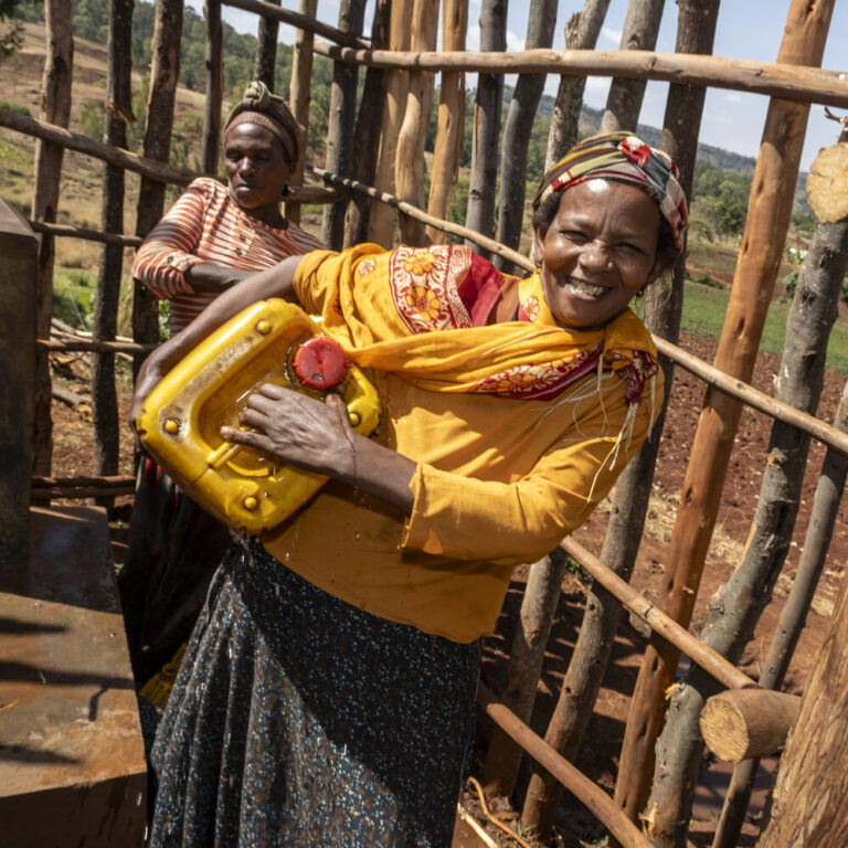 Two women are filling yellow jerry cans with water, helping rural communities gain access to clean water.