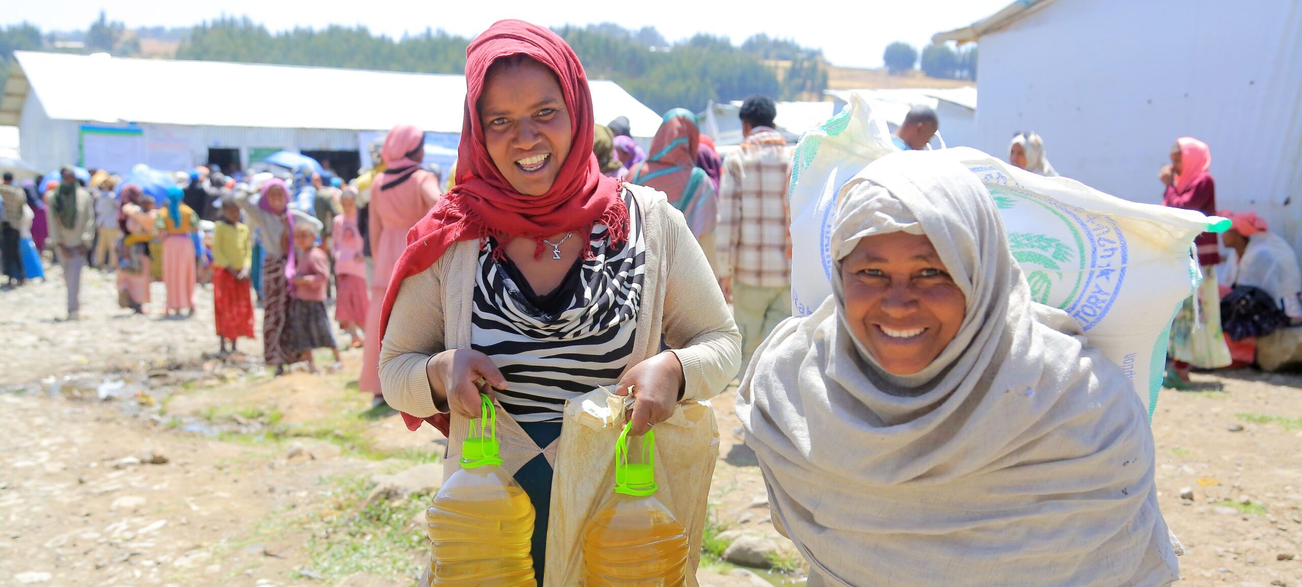 Two women holdig food ration from emergency relief.