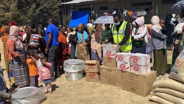A group of people standing arounf emergency relief food portions.