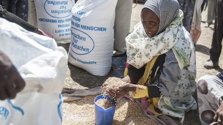 A women with grain in her hands from an emergency relief bag.