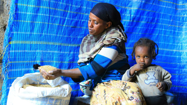 A women and her child infront of emergency relief bags.