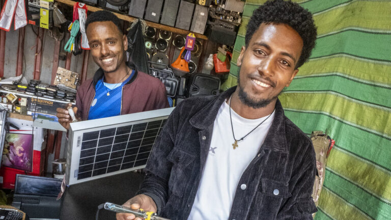 Two young men working on solar panels in an electronics and repair shop