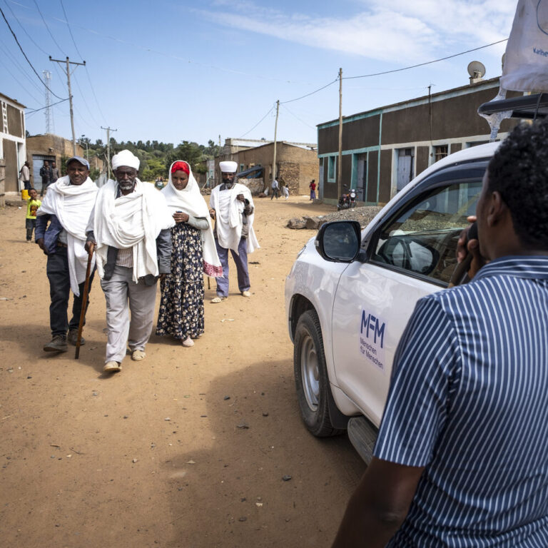 A MFM employee is informing people standing by a car with a microfon