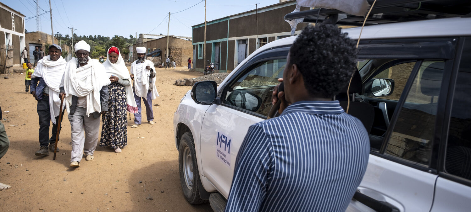 A MFM employee is informing people standing by a car with a microfon